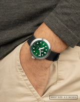 Man wearing Agumbe wristwatch with hand in pocket, featuring the deep green dial color with sunburst pattern and diver-style applied indices.