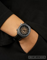 Woman wearing Earthshine watch with a matte-brown dial, hand in pocket, showing off its sleek design.