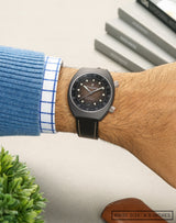 Man wearing Earthshine wristwatch on wrist, highlighting the pale-brown fume dial and space-inspired design elements.