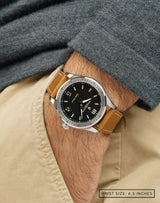 Man wearing Cover Drive Pavilion wristwatch with hand in pocket, featuring the matte-black dial and polished stainless steel case.