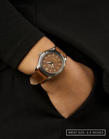 Woman wearing the Pitch watch with hand in pocket, highlighting its matte brown dial and classic design.
