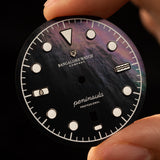 Man holding Mannar watch dial made from black mother of pearl having rare pattern and excellent color gradient.